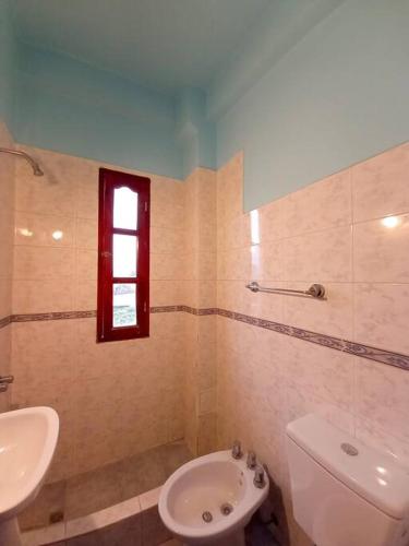 baño con lavabo y aseo y ventana en Sonqo Departamentos en San Salvador de Jujuy