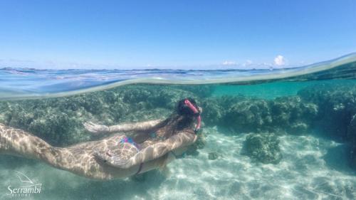 a person laying in the water in the ocean at Serrambi Resort in Porto De Galinhas