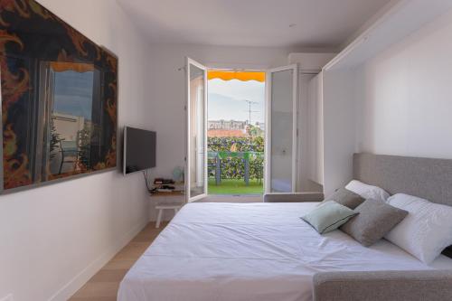 um quarto branco com uma cama e uma janela em Un Écrin au Suquet - Studio, clim, balcon, plage, Palais des Festivals em Cannes