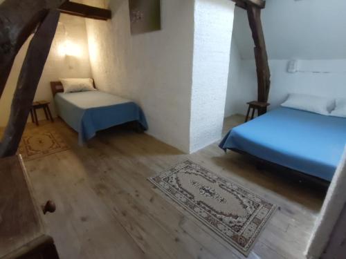 Cette chambre comprend 2 lits et un tapis. dans l'établissement Bienvenue en Transition 46 - Camoussel, à Najac
