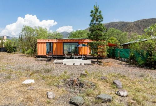 Mendoza San Isidro Cabaña في ميندوزا: منزل صغير برتقالي في حقل مع جبال في الخلفية