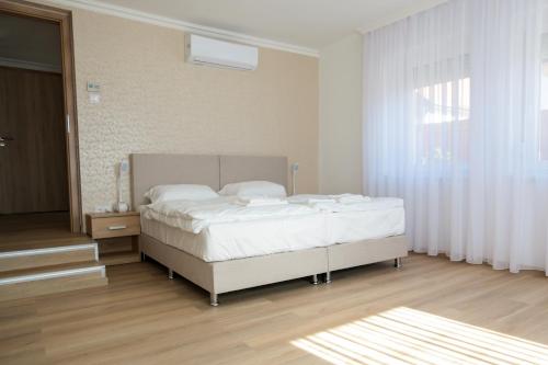 1 dormitorio con cama blanca y ventana en Markó Vendégház en Kiskőrös