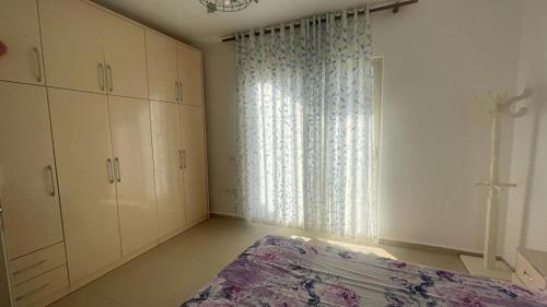 um quarto com uma cama e uma grande janela em apartament em Durrës