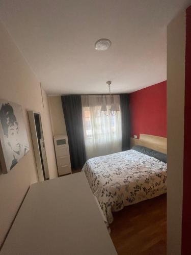um quarto com uma cama e uma parede vermelha em Apartamento acogedor próximo a playas y aeropuerto em La Coruña