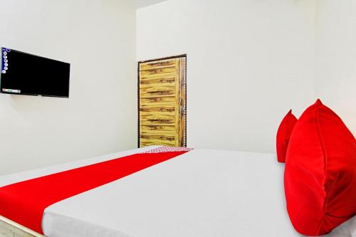 Schlafzimmer mit einem Bett mit roten Kissen und einem TV in der Unterkunft OYO Flagship Skyway Residency in Indraprast