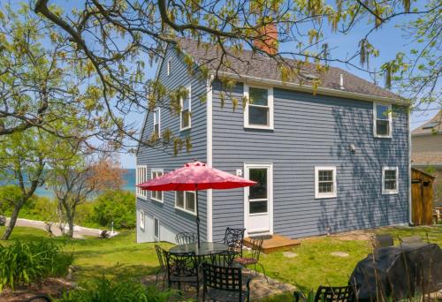 a table with an umbrella in front of a house at 83 Sagamore Road Sagamore Beach - - Cape Cod in Bourne