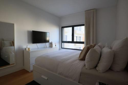 a white bedroom with a large bed and a window at River Terrace & Pool View - Seixal in Seixal