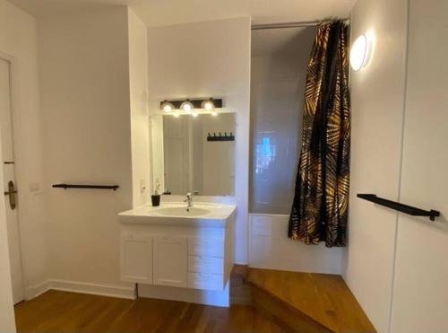 La salle de bains blanche est pourvue d'un lavabo et d'un miroir. dans l'établissement Appartement - 2 chambres - Parking voiture, à Mazamet
