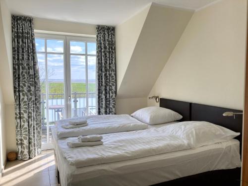 a bedroom with two beds and a large window at Ferienhaus Grodenblick Strandflieder Whg. 2 in Wangerooge