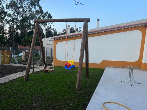 a swing set in a yard next to a house at Quinta da nogueira in Albergaria dos Doze