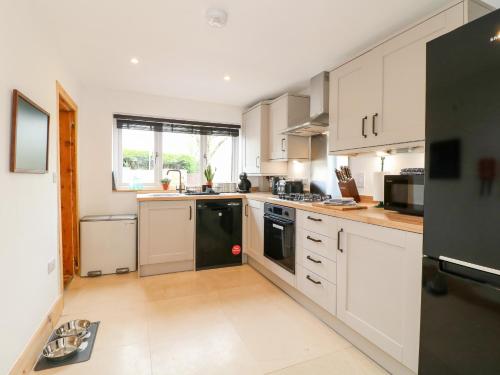 a kitchen with white cabinets and a black refrigerator at Valley View in Ashbourne