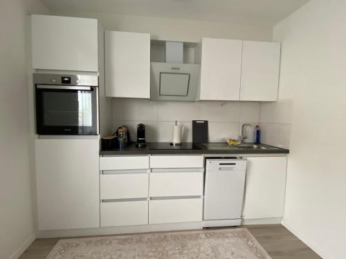a white kitchen with white cabinets and appliances at Dream Apartments in Hohenems