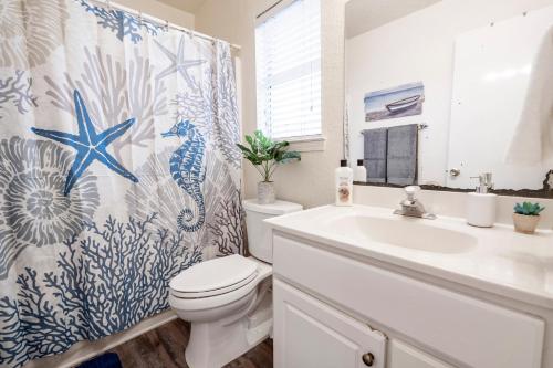 a bathroom with a shower curtain with a toilet and a sink at Oceanfront 2BR Cottage w Sunsets Views Comfy and Pet and Family Friendly in Freeport