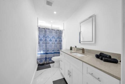 Baño blanco con lavabo y aseo en Modern Lux Pool Home Upscale, Spacious and Comfy, en Kendall