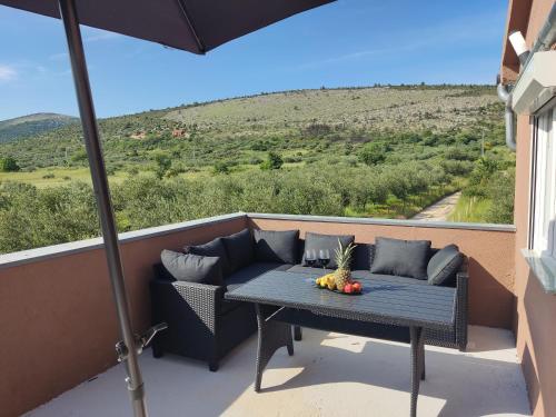 a patio with a table and a couch on a balcony at Holiday House Mablo with pool & jacuzzi in Šibenik