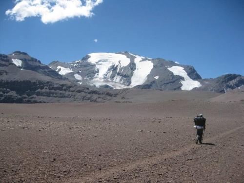 a person riding a bike in the desert with a snow covered mountain at CABAÑA LIRCAY - 2 habitaciones 48M2 para 4 personas in San Clemente