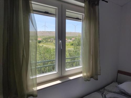 a bedroom with a window with a view of wind turbines at Holiday House Mablo with pool & jacuzzi in Šibenik