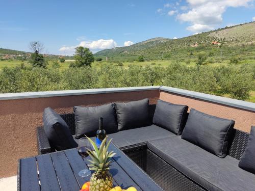 a couch on a balcony with a table with a pineapple at Holiday House Mablo with pool & jacuzzi in Šibenik