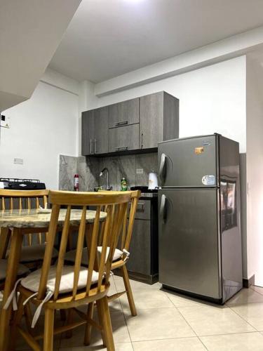 eine Küche mit einem Tisch und einem Kühlschrank aus Edelstahl in der Unterkunft APARTAMENTO AMOBLADO, LISTO PARA ESTRENAR. in Bello