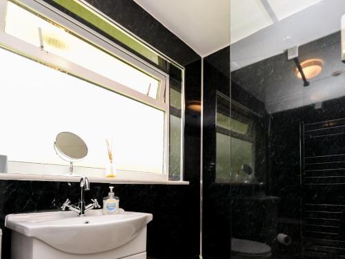 uma casa de banho com um lavatório, uma janela e um espelho. em 17 River Banks em Liskeard