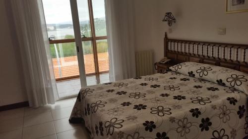 オ・グローベにあるHotel Bahiaのベッドルーム1室(ベッド1台、掛け布団、窓付)