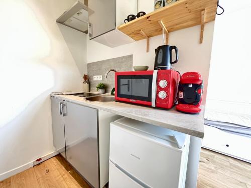 une petite cuisine avec un four micro-ondes rouge sur un comptoir dans l'établissement Le Colorado, studio à 5 min du centre-ville, à Poitiers