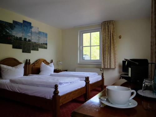 ein Schlafzimmer mit 2 Betten und einem Tisch mit einer Tasse drauf in der Unterkunft Hotel Heiderose Hiddensee in Neuendorf
