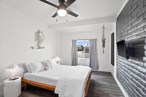 Dormitorio blanco con cama y pared de ladrillo en El Descanso in Meyer Park - Heated Pool en Tempe