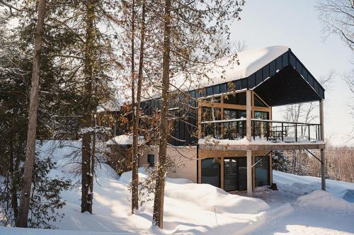 una casa en el bosque con nieve en el suelo en Unic loft Sapa - Massif Charlevoix, Mont-St-Anne, en Saint-Joachim