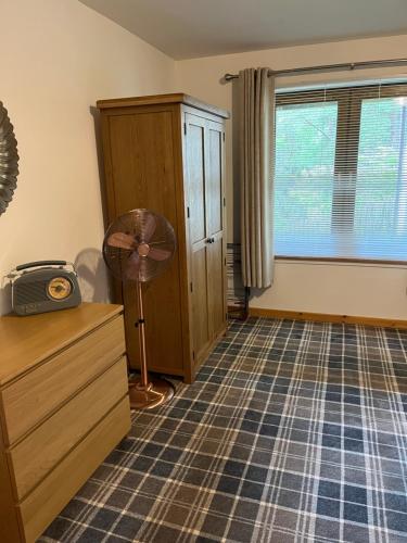 a room with a fan and a dresser and a window at Tigh Stobban Apartment 1 in Fort William