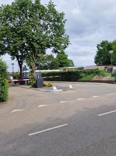 an empty parking lot with a tree and a building at Ferienhaus Lathum früher Chalet Familienzeit in Lathum