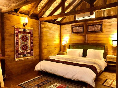 a bedroom with a bed in a room with wooden walls at The 2 Magpies, Hunza in Alīābād