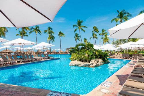 a swimming pool with chairs and umbrellas at a resort at Sheraton Buganvilias Puerto Vallarta in Puerto Vallarta