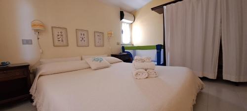 Un dormitorio con una cama blanca con toallas. en Appartamento Fiume, en Villasimius