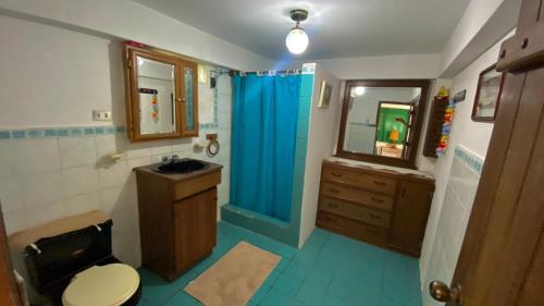 baño con cortina de ducha azul y lavamanos en La Casa Del Arbol, en Olón