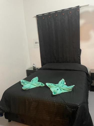 a black bed with two green pillows on it at La Florida Hotel in El Colegio