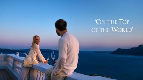a man and a woman standing on the top of a building at Oia Mansion in Oia