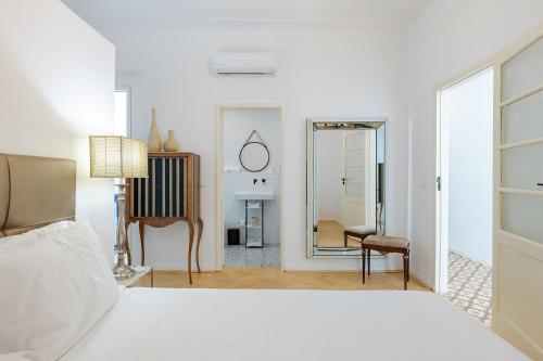 a white bedroom with a bed and a mirror at Casa Largo da Mó in Portimão