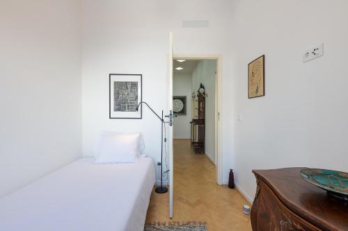 a white bedroom with a bed and a hallway at Casa Largo da Mó in Portimão