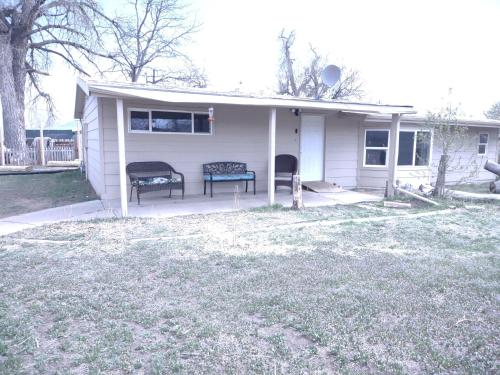 a small white house with two chairs in the yard at 3 Bedroom By River Park & Trails in Loveland