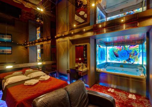 a bedroom with a large bed and a tub at ALFA HOTEL in Skaramangás