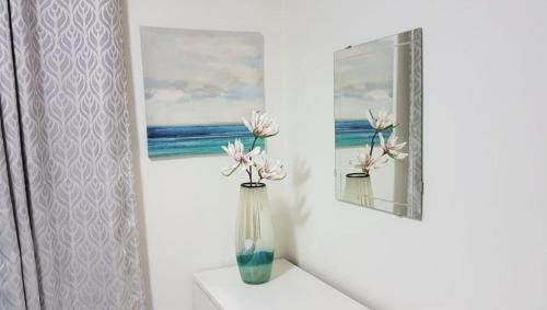 a vase with flowers sitting on a shelf next to a painting at Moderno Apartamento amueblado Full 3 habitaciones, wifi, Netflix in Santiago de los Caballeros