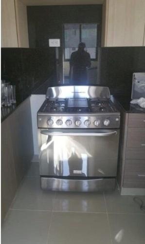 a stove in a kitchen with a person in the background at Moderno Apartamento amueblado Full 3 habitaciones, wifi, Netflix in Santiago de los Caballeros