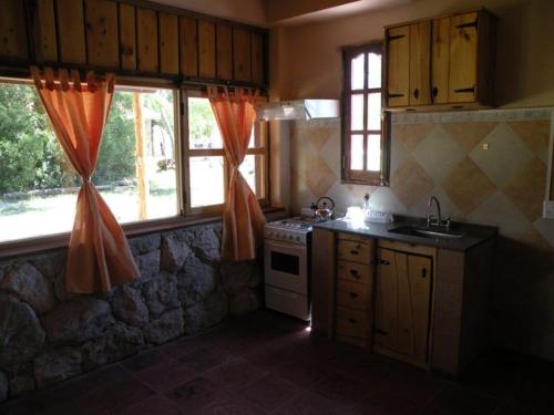 una cucina con piano cottura e alcune finestre di Apart Cabañas Altos de Vaquerias a Valle Hermoso
