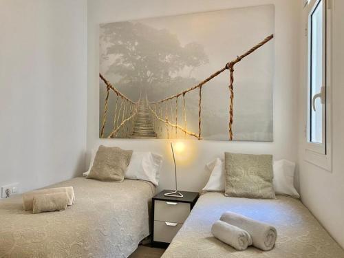 バルセロナにある2 BDR EIXAMPLE APARTMENTの壁に橋の絵画が飾られた客室で、ベッド2台が備わります。