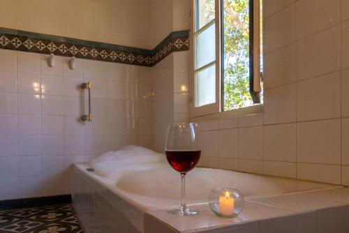 a glass of wine sitting on a bath tub with a candle at Hotel El Manantial del Silencio in Purmamarca