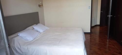 1 cama con sábanas blancas y almohadas en una habitación en Dpto de categoría en Salta