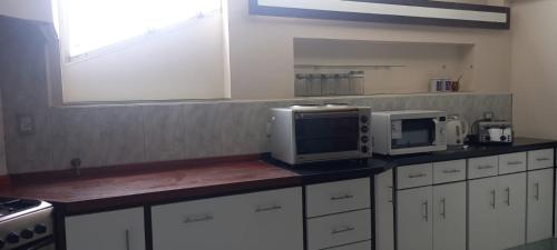 cocina con armarios blancos y encimera con microondas en Dpto de categoría en Salta