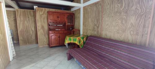 une chambre avec un banc et une armoire en bois dans l'établissement fleurs de canne, à Petit-Bourg