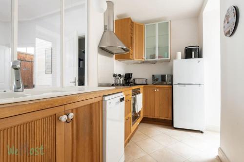 une cuisine avec des armoires en bois et un réfrigérateur blanc dans l'établissement Maison de Ville, Hyper Centre, 8p, 105m2, à Pornic